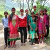 A group adorned in tika return to their home village